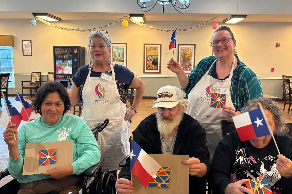 Two teaching artists and three residents hold star shaped paintings and wave Texas flags.
