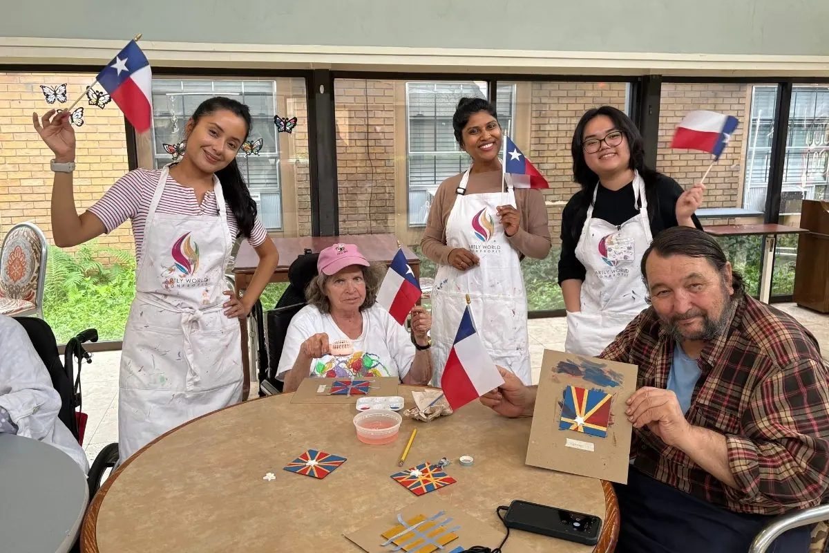 Residents and teaching artists hold painted kite shapes and small flags at a table.
