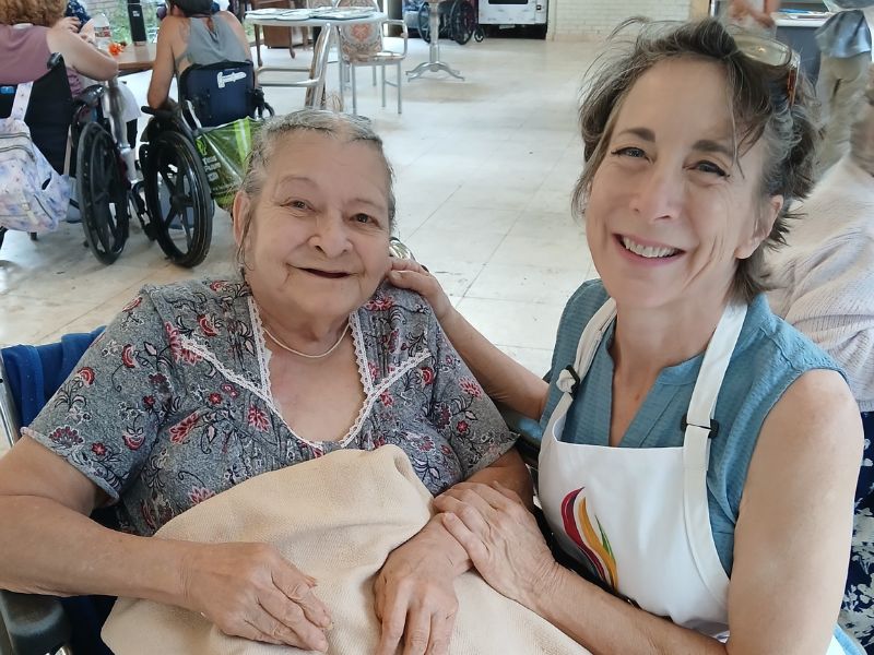 An elder living with dementia and a caregiver drumming together in a Memory Arts circle.