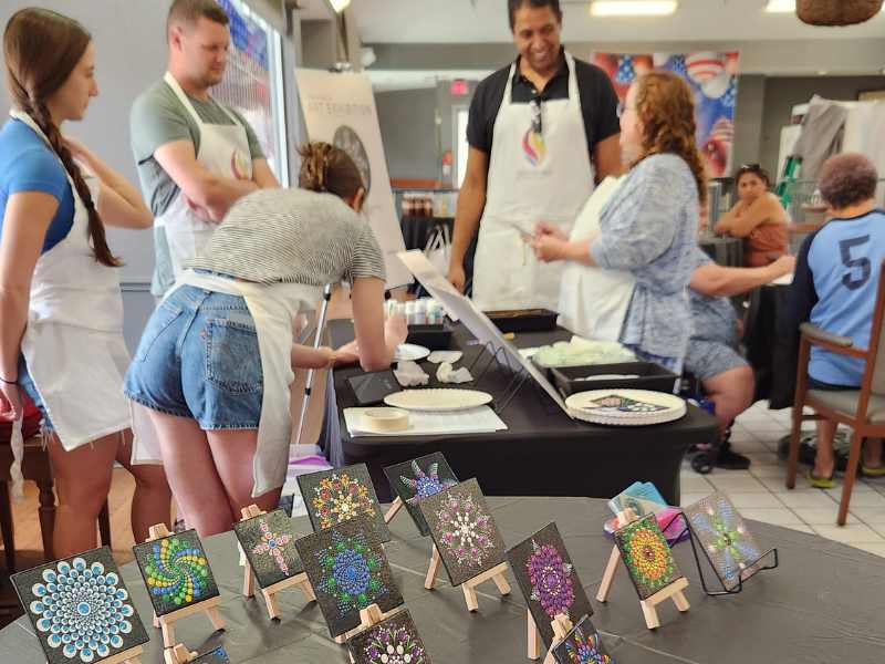Smiling teaching artists guiding community members through a collaborative painting session at an Artly World event in Austin, Texas