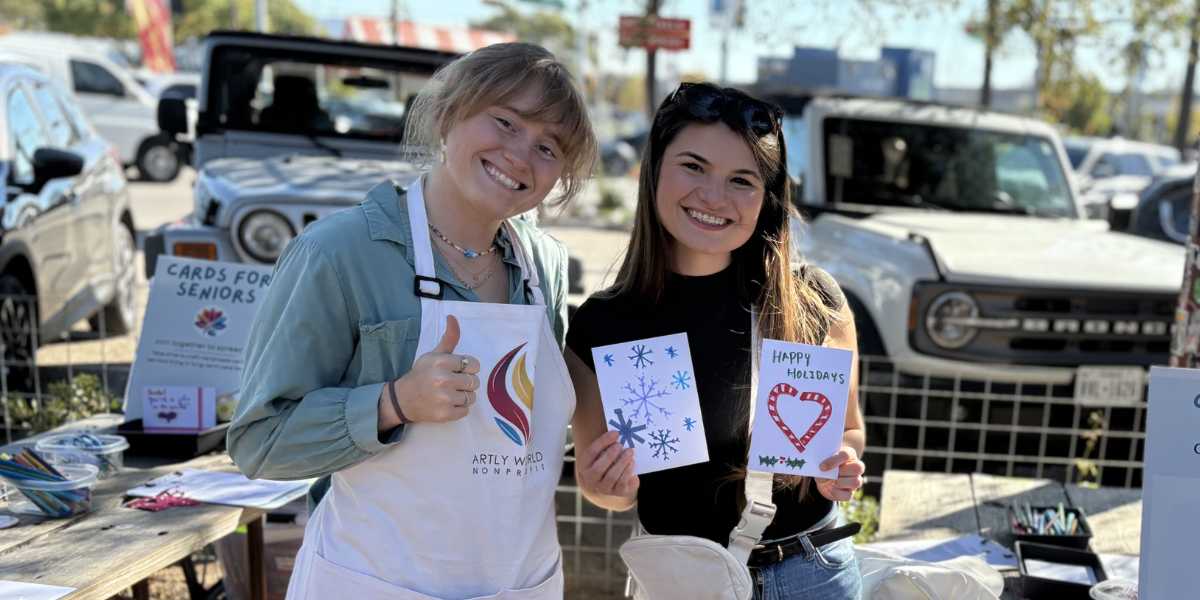 Artly World volunteers setting up tables and sitting beside first-time artists at a free community art session in Austin, Texas