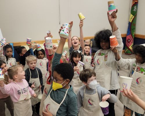 Grade school students in Artly World aprons cheering with their handmade decorated cups.